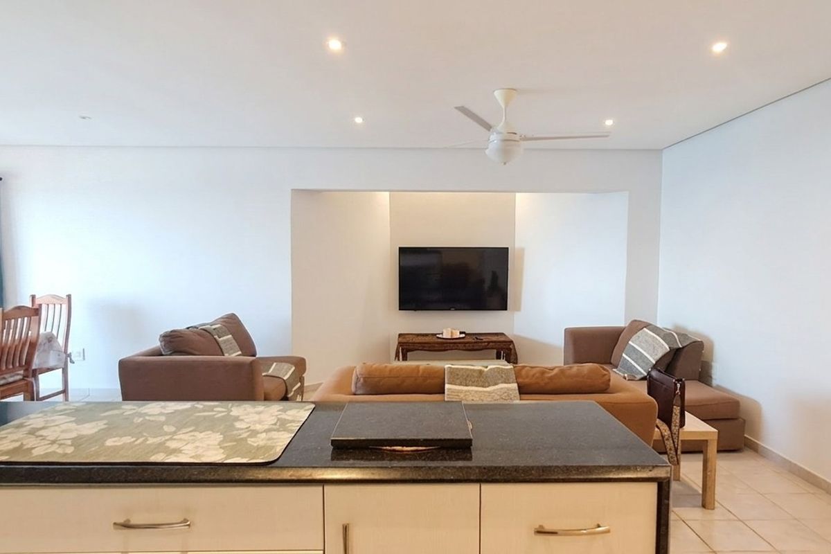 Spacious open-plan living and kitchen area featuring tiled floors, recessed lighting, a ceiling fan, and a modern kitchen island with granite countertops.