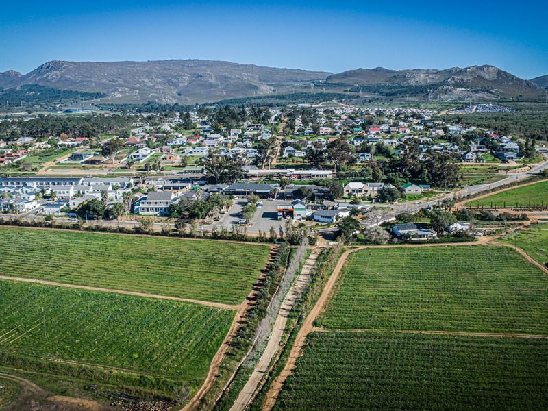 An aerial view of the surrounding neighbourhood and landscape, showcasing the property's location within the community and proximity to agricultural fields and mountains.