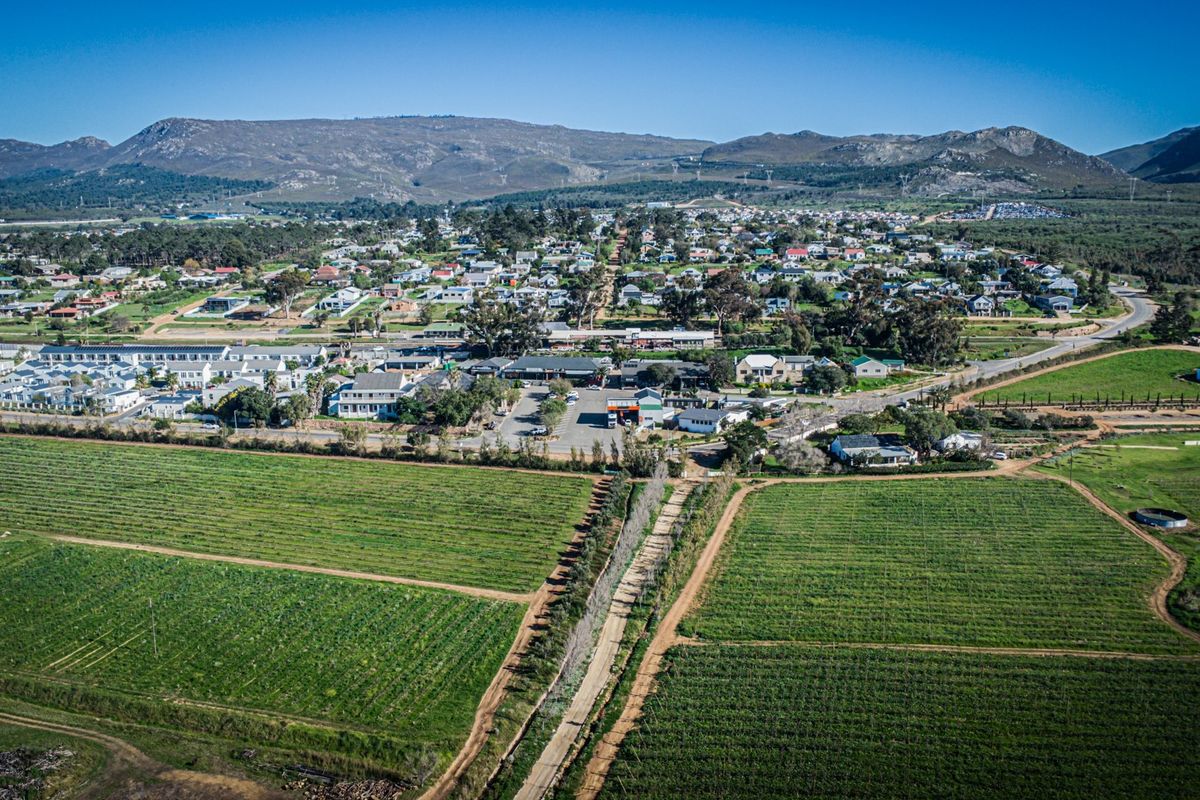 An aerial view of the surrounding neighbourhood and landscape, showcasing the property's location within the community and proximity to agricultural fields and mountains.
