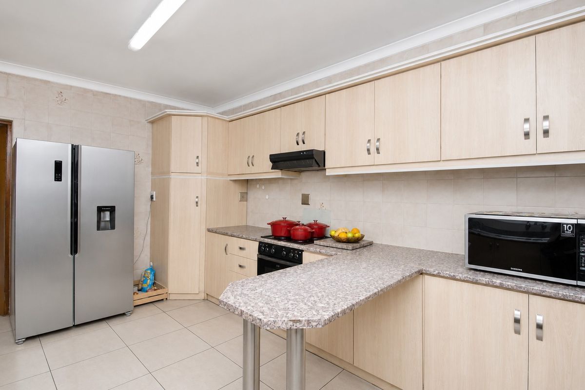 Functional kitchen featuring light wood-tone cabinetry, laminate countertops, ceramic tile backsplash, and a convenient breakfast bar extension.