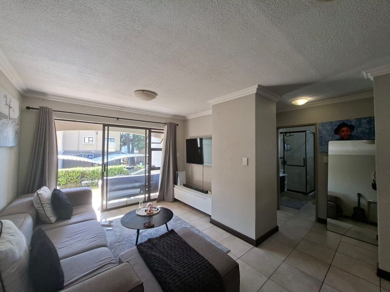 Open-plan living area featuring tiled flooring, ceiling cornices, and a large sliding glass door providing access to the patio area.