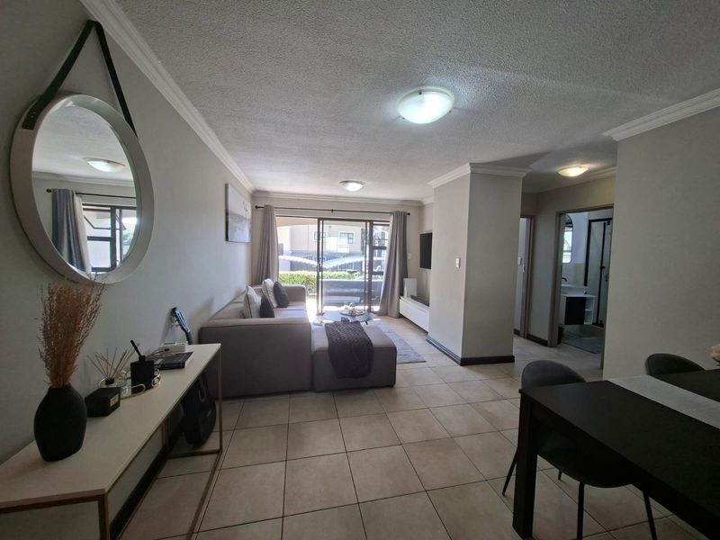 Open plan living area featuring tiled flooring, neutral walls, and sliding glass doors leading to an outdoor space.