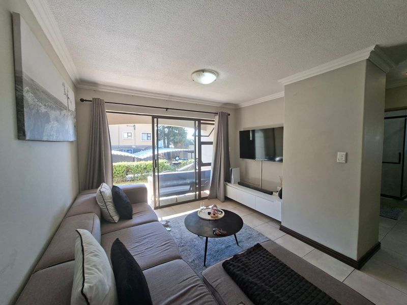 A comfortable living room featuring tiled flooring, a sliding glass door leading to an outdoor area, and neutral wall finishes.