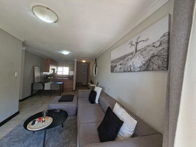 Open-plan living area featuring tiled floors and a functional kitchen with built-in cabinetry, creating a cohesive and practical living space.