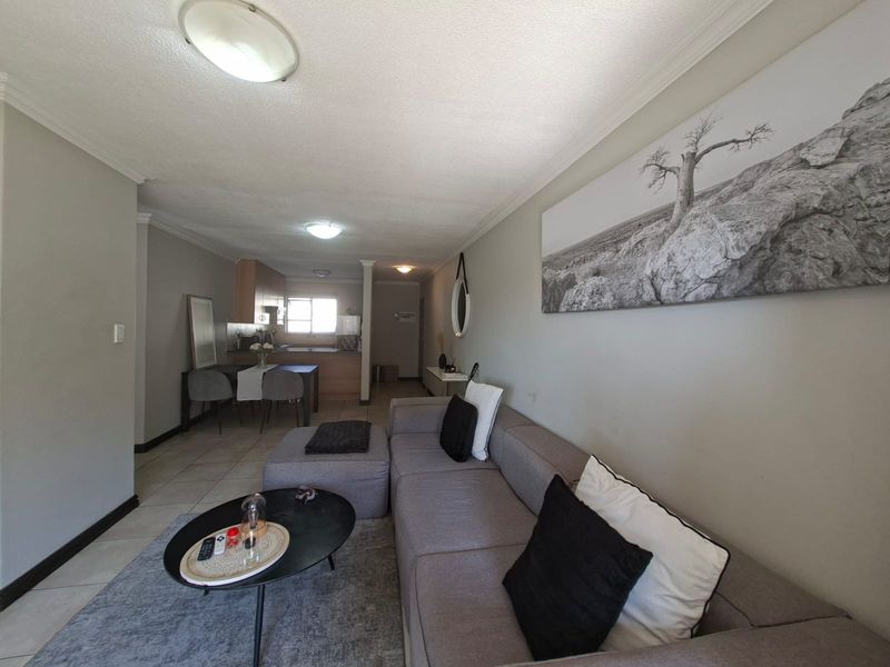 Open plan living and kitchen area featuring tiled flooring, neutral wall tones, and functional built-in cabinetry in the kitchen space.