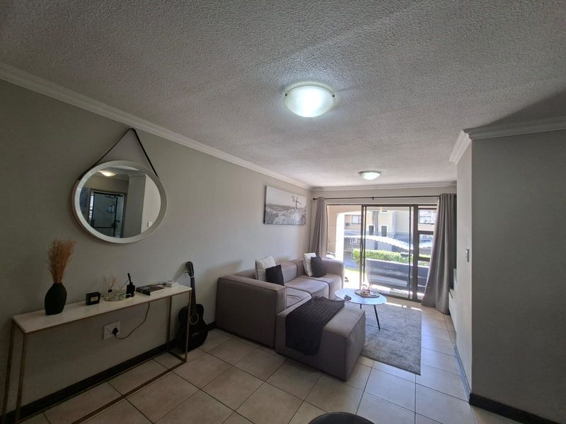 A comfortable living room featuring tiled flooring, coved ceilings, and large sliding glass doors that provide access to an outdoor area.