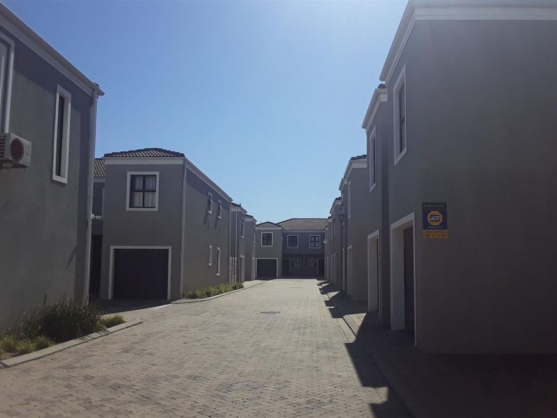 A view of the paved complex driveway flanked by modern apartment buildings with garage access and exterior security features.
