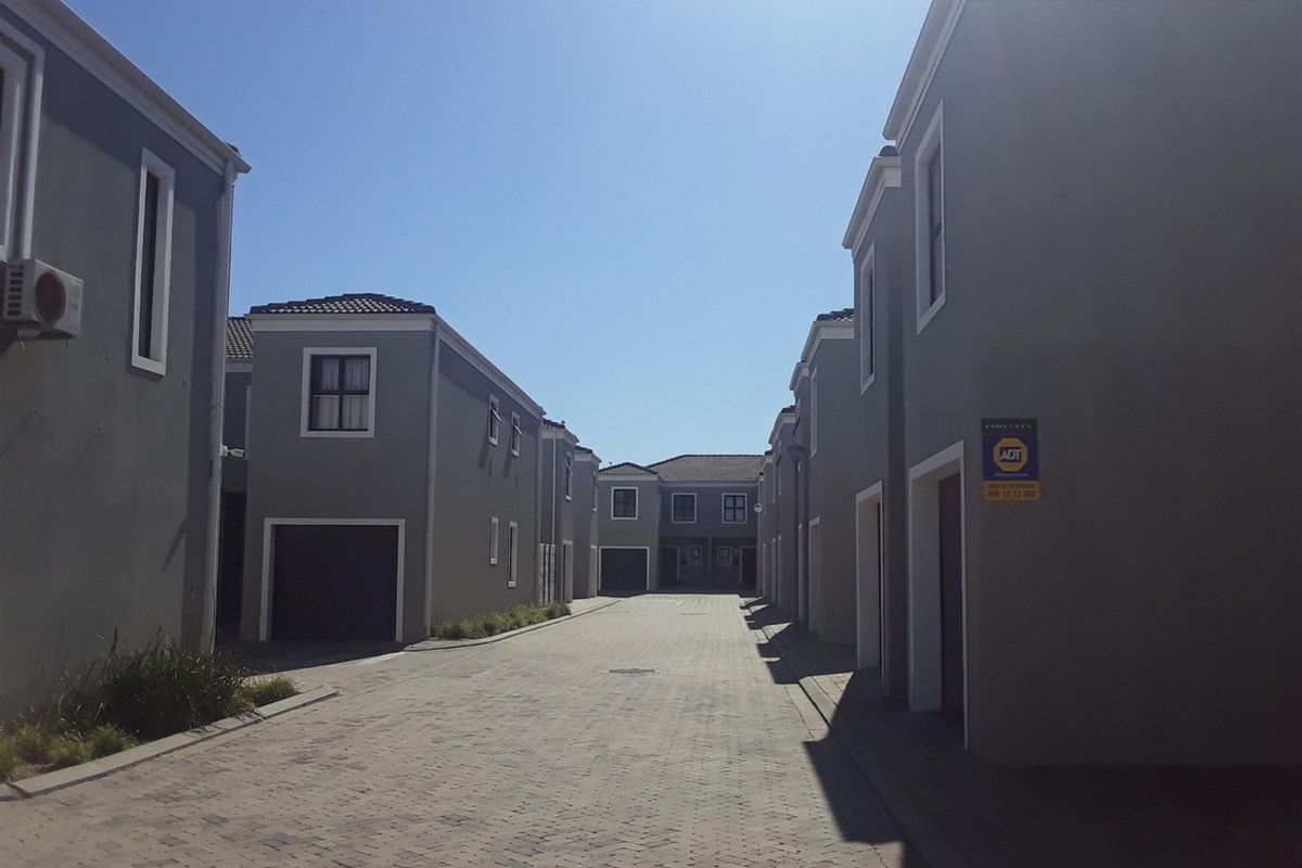 A view of the paved complex driveway flanked by modern apartment buildings with garage access and exterior security features.