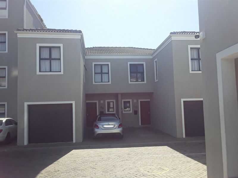Front elevation of a modern apartment complex featuring paved driveway access, integrated garage doors, and neutral exterior wall finishes.