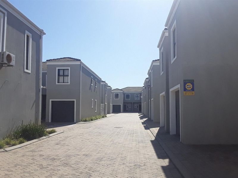 A view of the paved driveway and access road within a modern apartment complex, featuring multiple garage entrances and grey exterior facades.