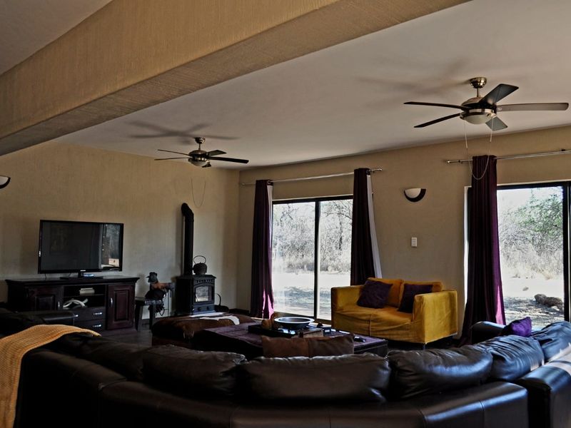 Spacious living room featuring a wood-burning stove, dual ceiling fans, and large sliding glass doors providing natural light and garden access.