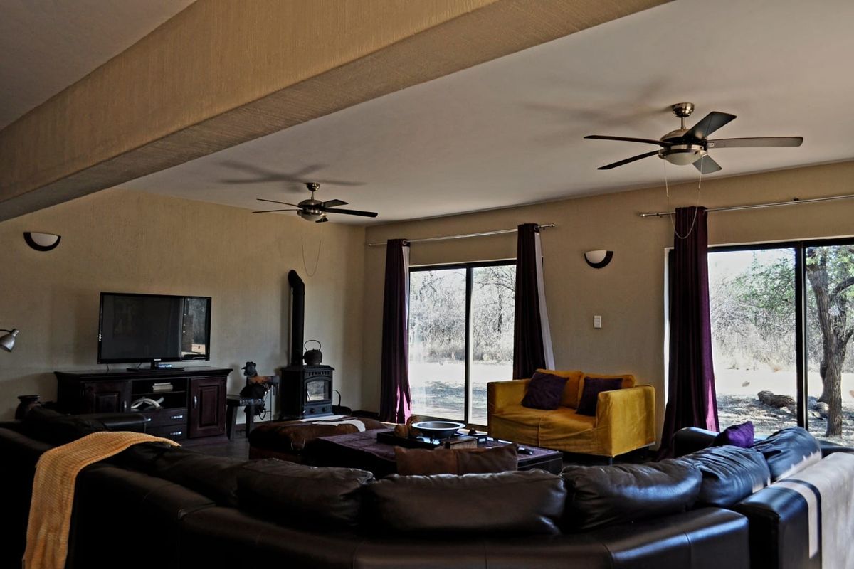 Spacious living room featuring a wood-burning stove, dual ceiling fans, and large sliding glass doors providing natural light and garden access.