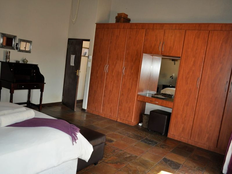 A bedroom featuring tiled flooring and extensive built-in wooden cabinetry with an integrated vanity mirror.