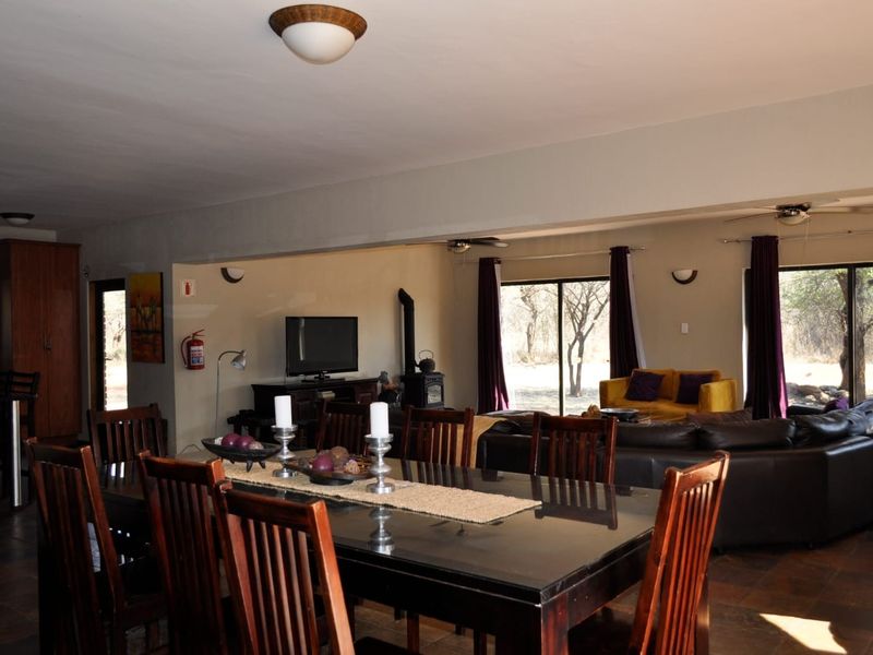 Spacious open-plan living and dining area featuring tiled floors, a wood-burning fireplace, and large sliding glass doors providing natural light and garden access.