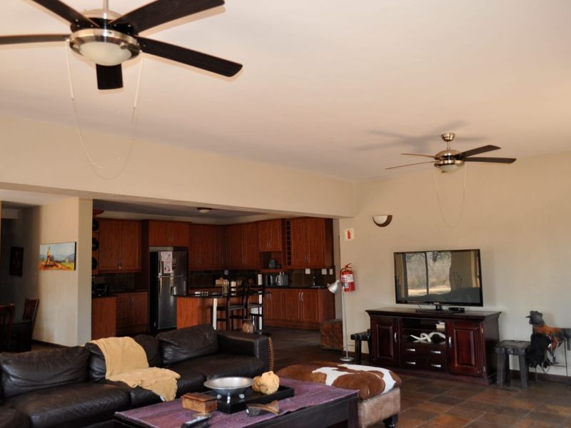 Spacious open-plan living area featuring tiled floors, ceiling fans, and a functional kitchen with dark wood cabinetry.