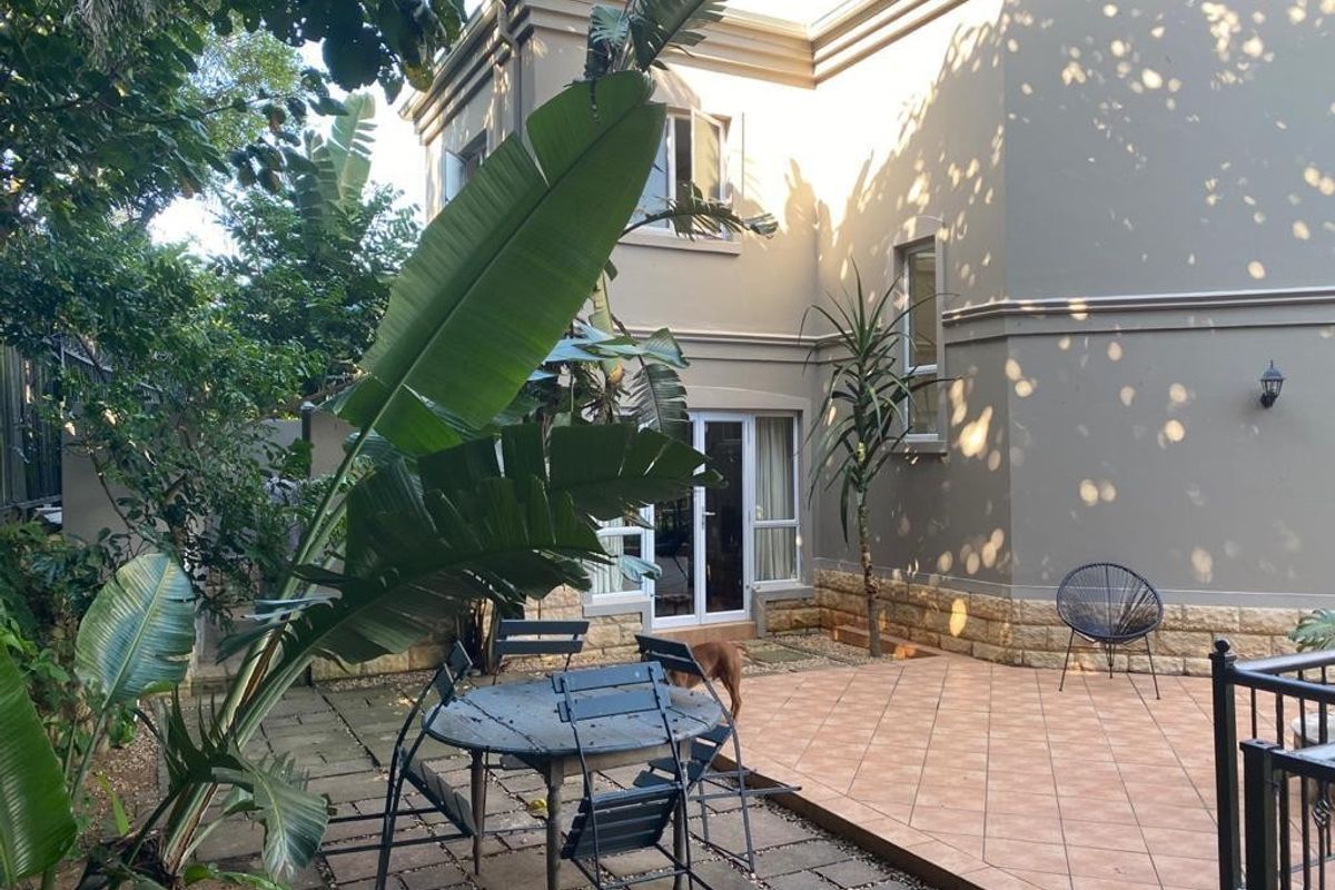 A private rear patio area featuring tiled flooring, stone-clad wall accents, and direct access to the interior through sliding glass doors.
