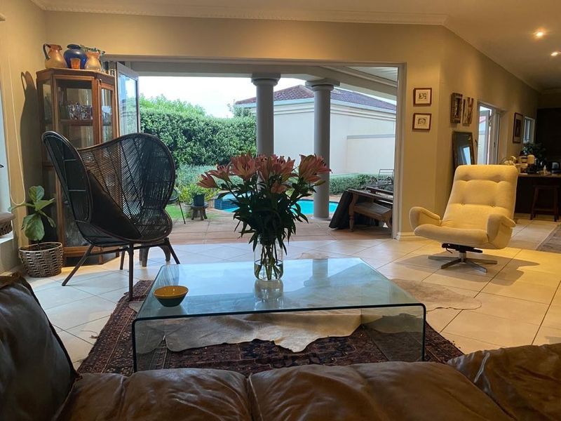 Spacious open-plan living area featuring large sliding glass doors that open onto a covered patio and pool area, creating a seamless indoor-outdoor flow.
