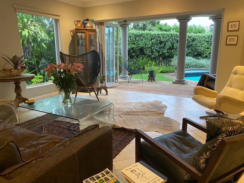 Spacious living room featuring large windows and bi-fold doors opening onto a covered patio with pool views.