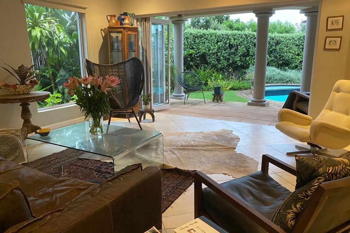 Spacious living room featuring large windows and bi-fold doors opening onto a covered patio with pool views.