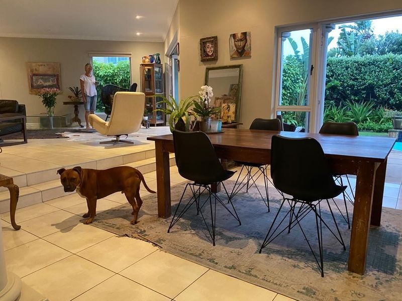 Spacious open-plan living and dining area featuring tiled flooring, recessed lighting, and large sliding glass doors providing access to the garden.