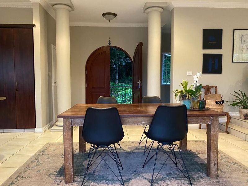 Dining area featuring decorative columns, arched double doors leading to the exterior, and built-in cabinetry with neutral tiled flooring.