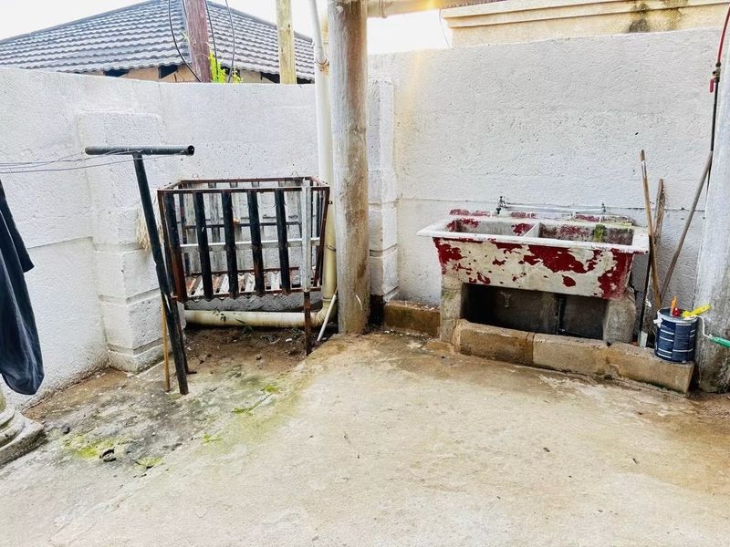 Outdoor laundry area featuring a concrete double wash trough and masonry walls, providing a functional utility space for the property.