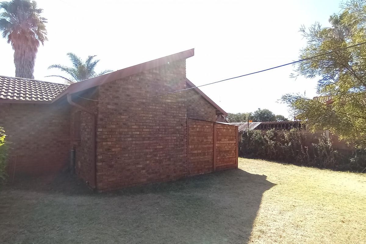 A view of the rear exterior of the house featuring a brick facade, tiled roof, and a private garden area with a brick boundary wall.