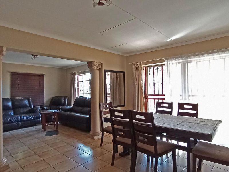 Open plan living and dining area featuring ceramic floor tiles, decorative columns, and access to the exterior via a sliding glass door.
