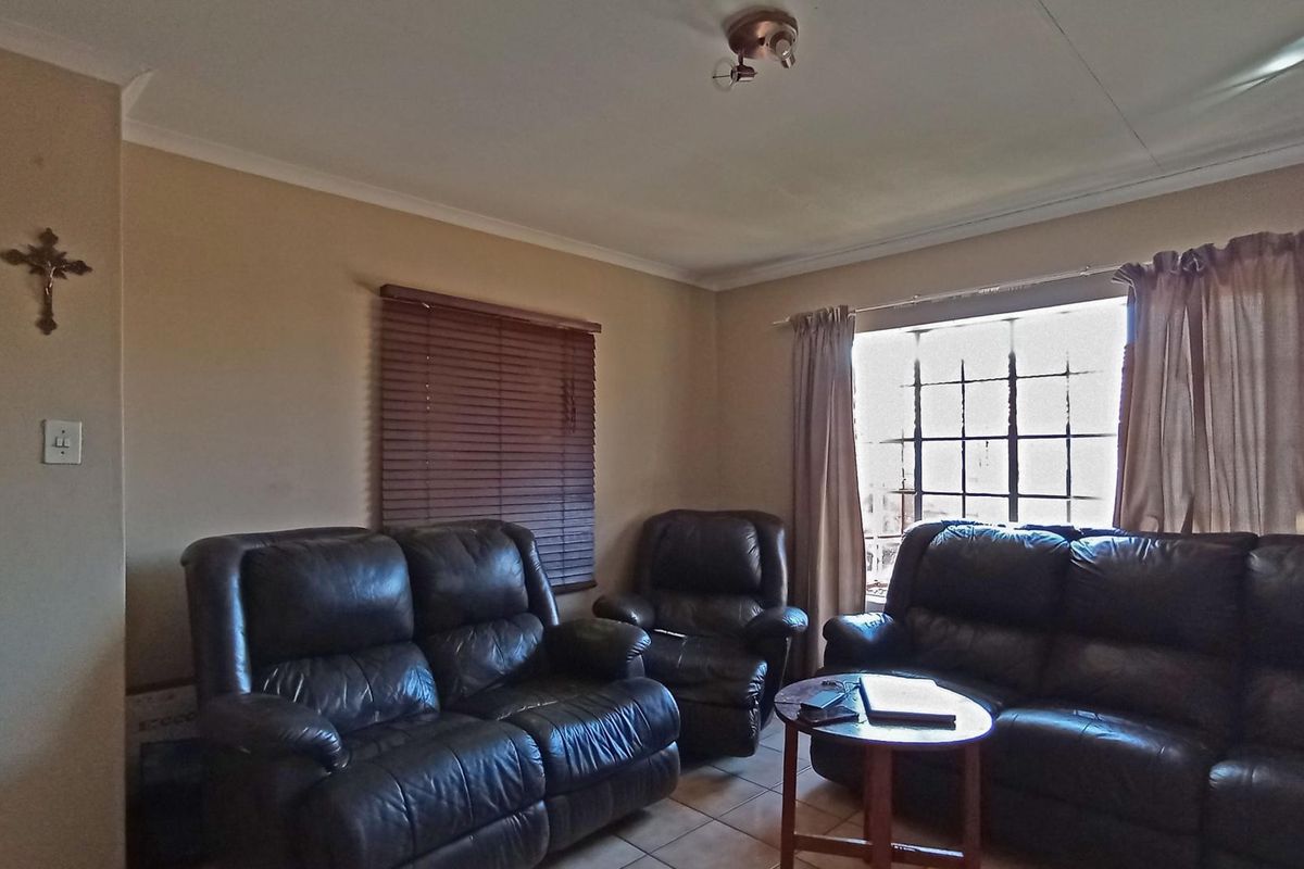 A functional living room featuring tiled flooring, window blinds, and a central ceiling light fixture, providing a comfortable and practical space.