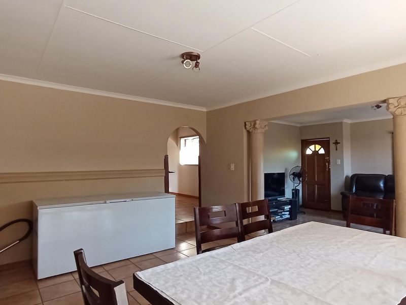 Open plan living and dining area featuring decorative columns, tiled flooring, and an arched transition to the hallway.