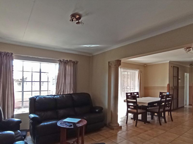 Open-plan living and dining area featuring decorative columns, tiled flooring, and neutral wall finishes, providing a versatile space for family living.