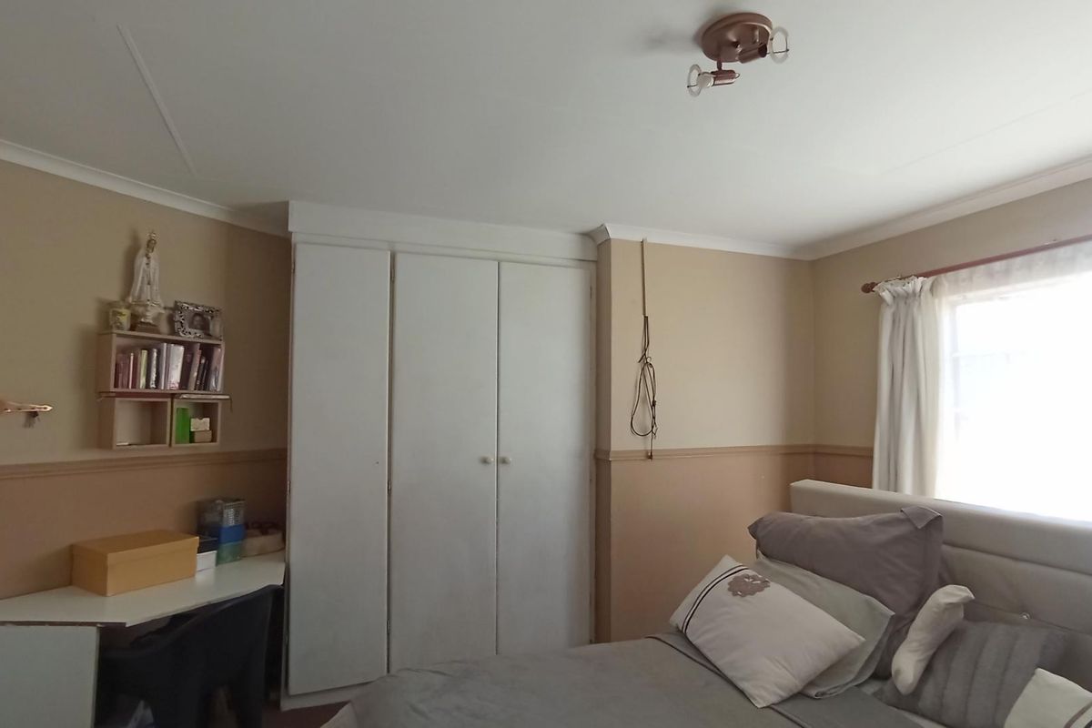 A bedroom featuring built-in cupboards, a dado rail, and a ceiling-mounted light fixture, offering a functional space with neutral wall tones.