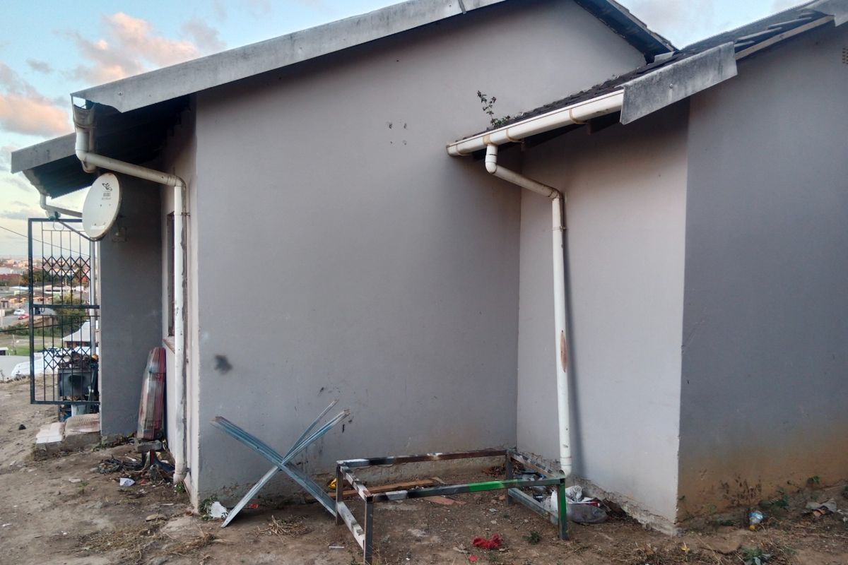 Rear exterior view of the house showing painted walls, guttering system, and a security gate.