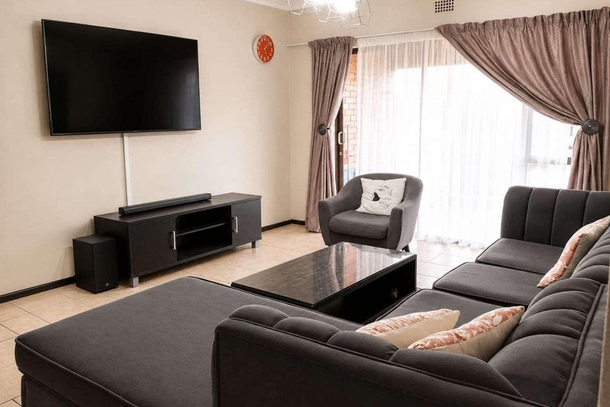 A well-maintained living room featuring tiled flooring and a large sliding glass door that provides natural light and access to the exterior.