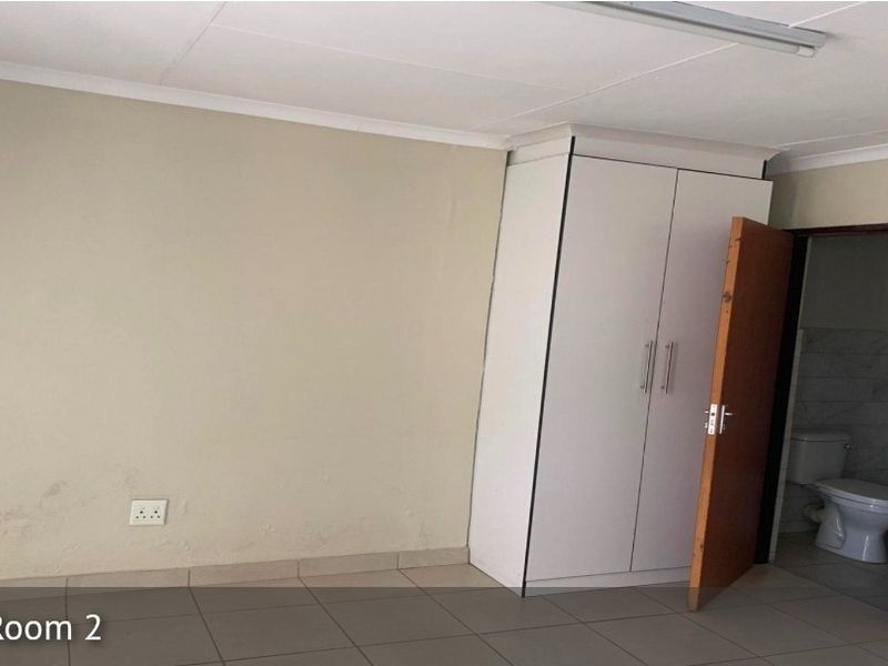 A vacant bedroom featuring tiled flooring, a built-in wardrobe, and direct access to an en-suite bathroom.