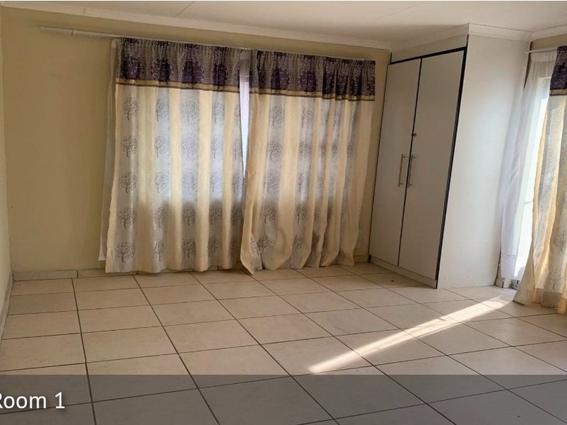 A spacious bedroom featuring neutral tiled flooring and a built-in wardrobe, offering a clean and functional space ready for personalization.