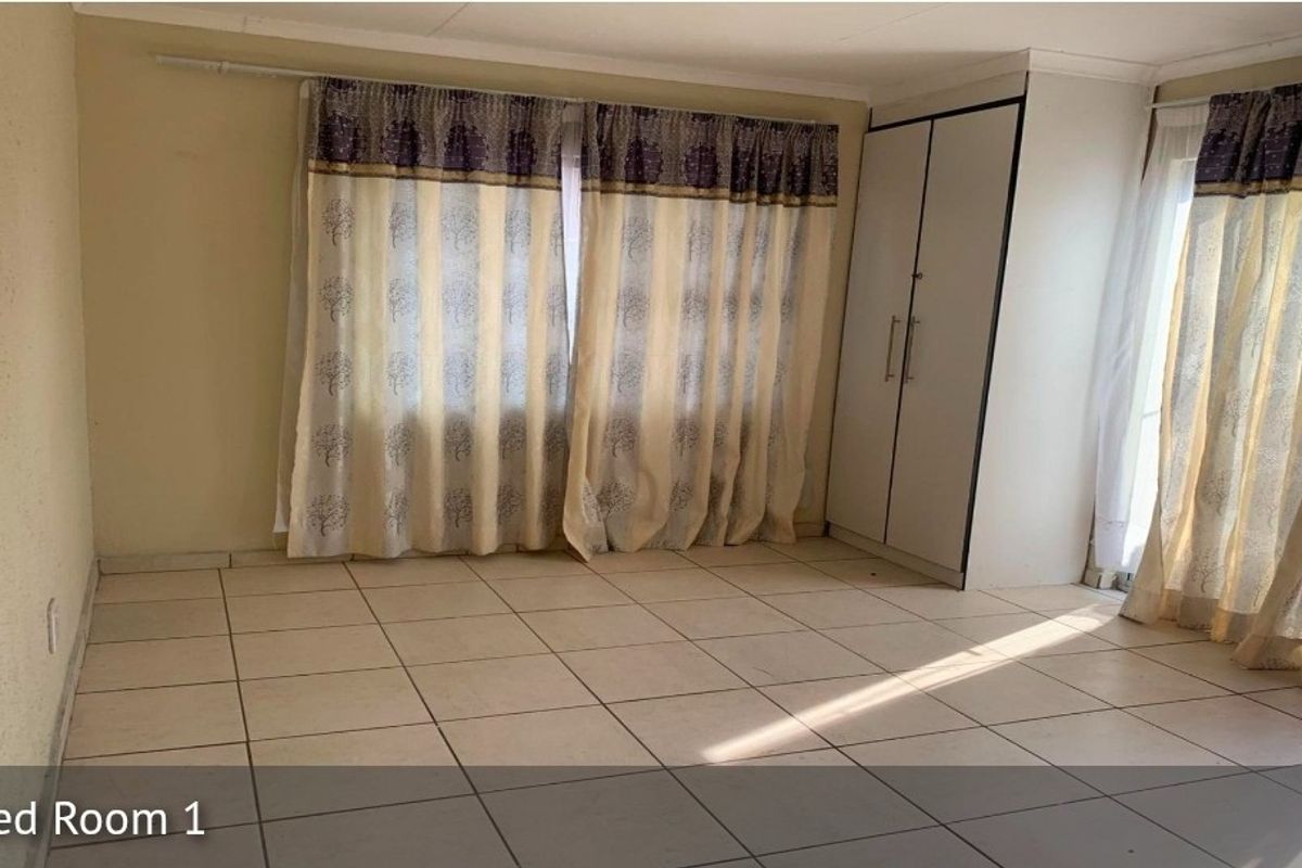 A spacious bedroom featuring neutral tiled flooring and a built-in wardrobe, offering a clean and functional space ready for personalization.