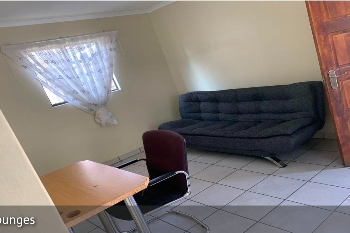 A simple living room area featuring tiled flooring and a timber door.