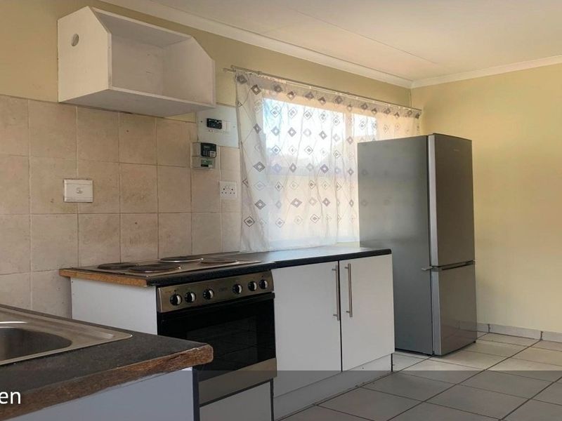 A functional kitchen featuring tiled splashbacks, laminate countertops, a built-in stove, and tiled flooring, offering a practical layout for daily meal preparation.
