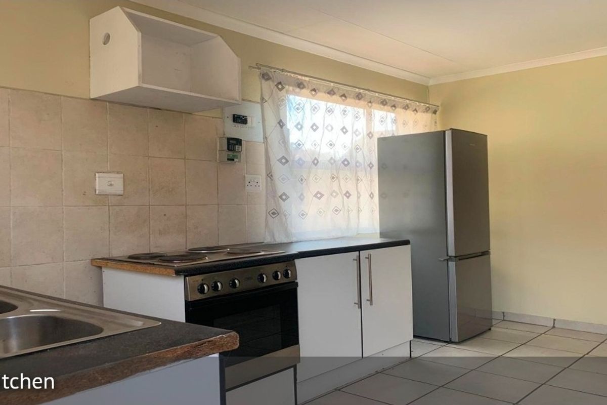 A functional kitchen featuring tiled splashbacks, laminate countertops, a built-in stove, and tiled flooring, offering a practical layout for daily meal preparation.