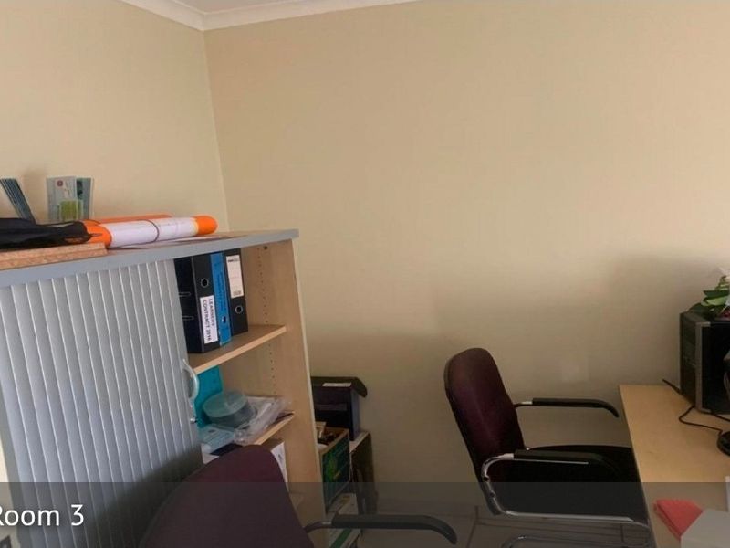 A functional bedroom space currently utilized as a home office, featuring neutral wall finishes and coving.