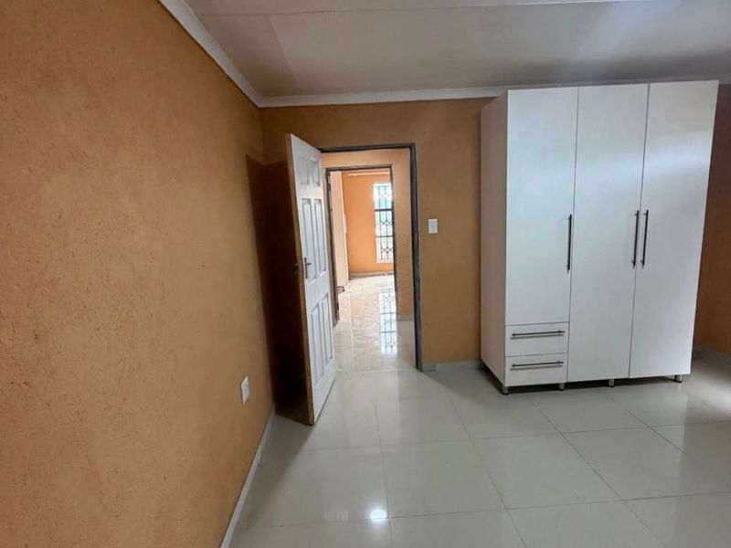 A bedroom featuring tiled flooring, a built-in wardrobe, and access to an adjoining hallway.