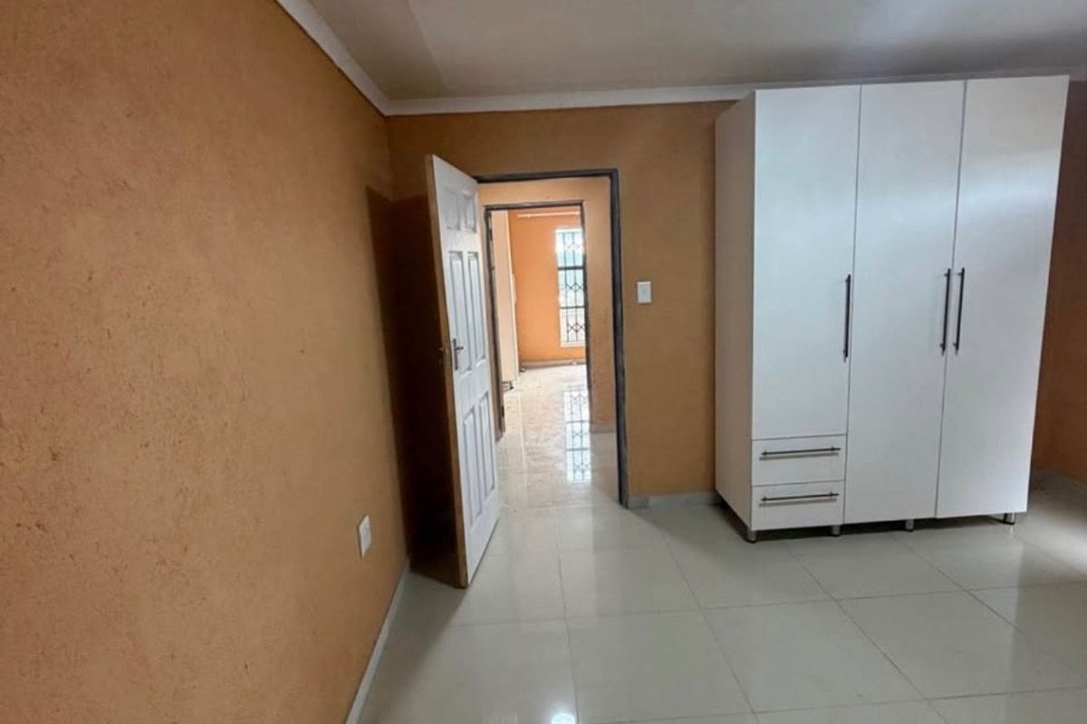 A bedroom featuring tiled flooring, a built-in wardrobe, and access to an adjoining hallway.