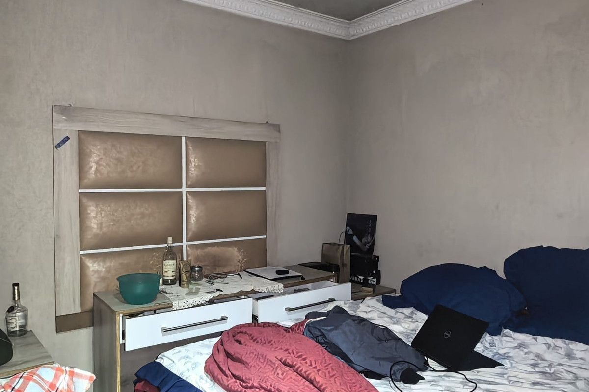 A bedroom featuring a built-in headboard and decorative ceiling cornice, requiring cosmetic updates to the wall and ceiling finishes.