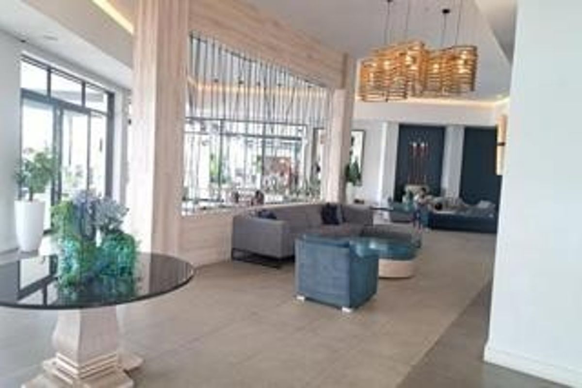 A spacious, modern open-plan living area featuring high-quality tiled flooring, decorative timber slat room dividers, and elegant pendant lighting.