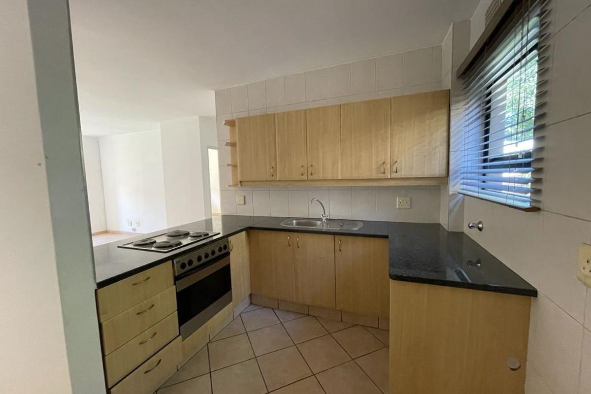 A functional kitchen featuring laminate cabinetry, dark countertops, built-in oven and hob, and tiled flooring, offering a clean space ready for modern updates.