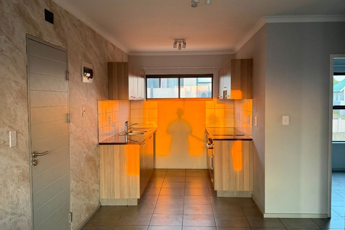 A clean, functional kitchen featuring wood-finish cabinetry, tiled flooring, and a tiled backsplash, offering a neutral space ready for personalization.