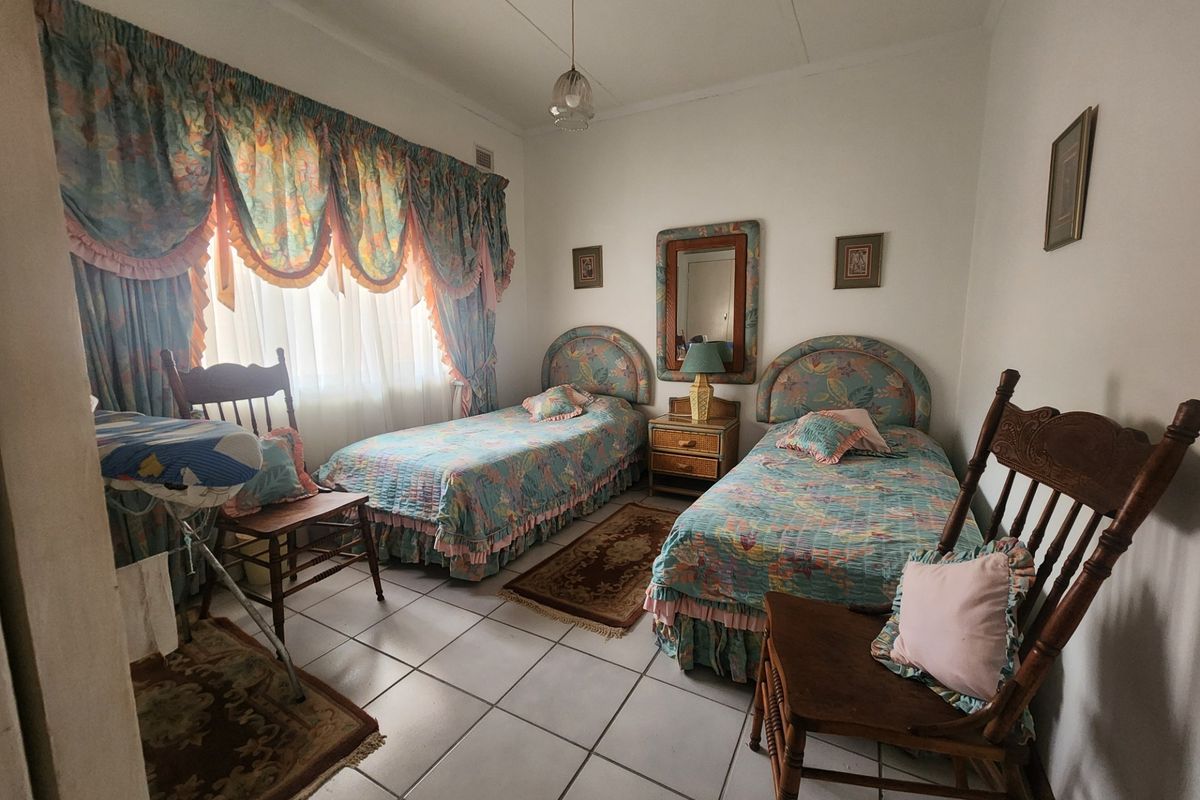 A bedroom featuring tiled flooring and a window with curtain rails, offering a functional space ready for modern updates.