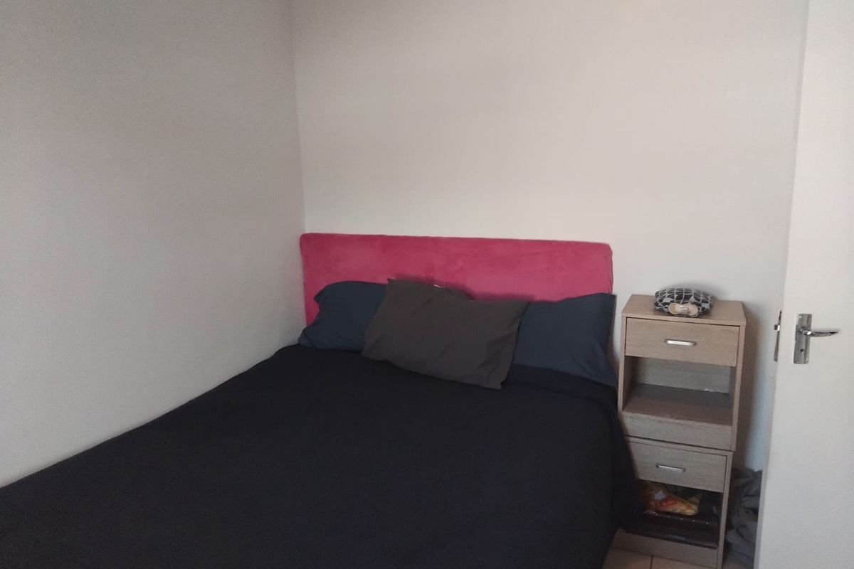 A simple bedroom featuring neutral walls and tiled flooring, providing a functional space for rest.