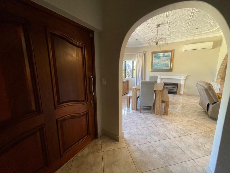 Welcoming entrance hall featuring an arched doorway leading into an open-plan living and dining area with tiled floors and a decorative ceiling.